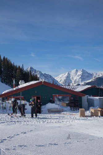 Ski patrol leaving Cloud Nine Alpine Bistro with Maroon Bells in the background