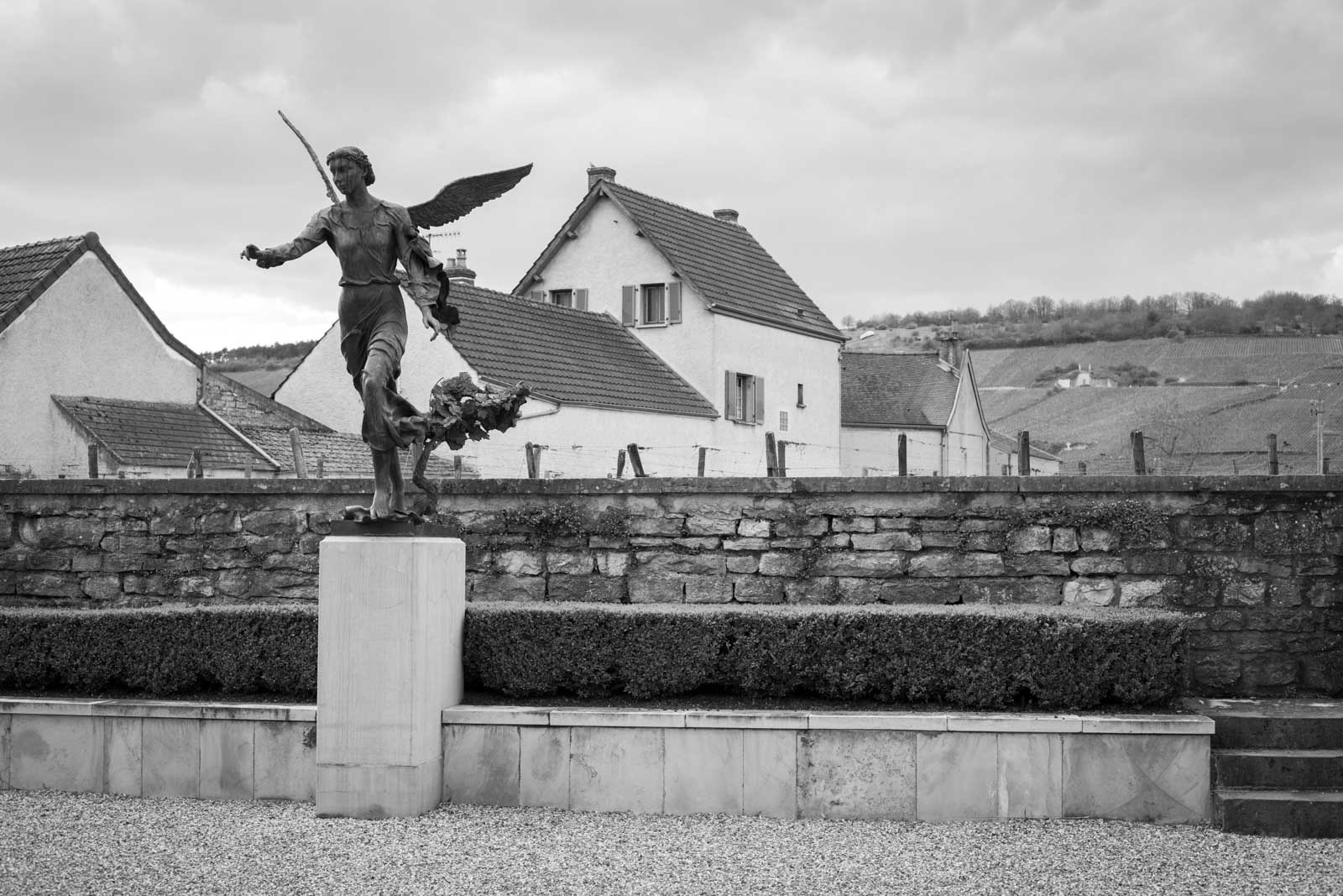 The angel-crowned courtyard at Domaine de la Romanée-Conti, in the village of Vosne-Romanée. The Grand Cru vineyard of Romanée-St-Vivant is just beyond the stone wall. ©Kevin Day / Opening a Bottle