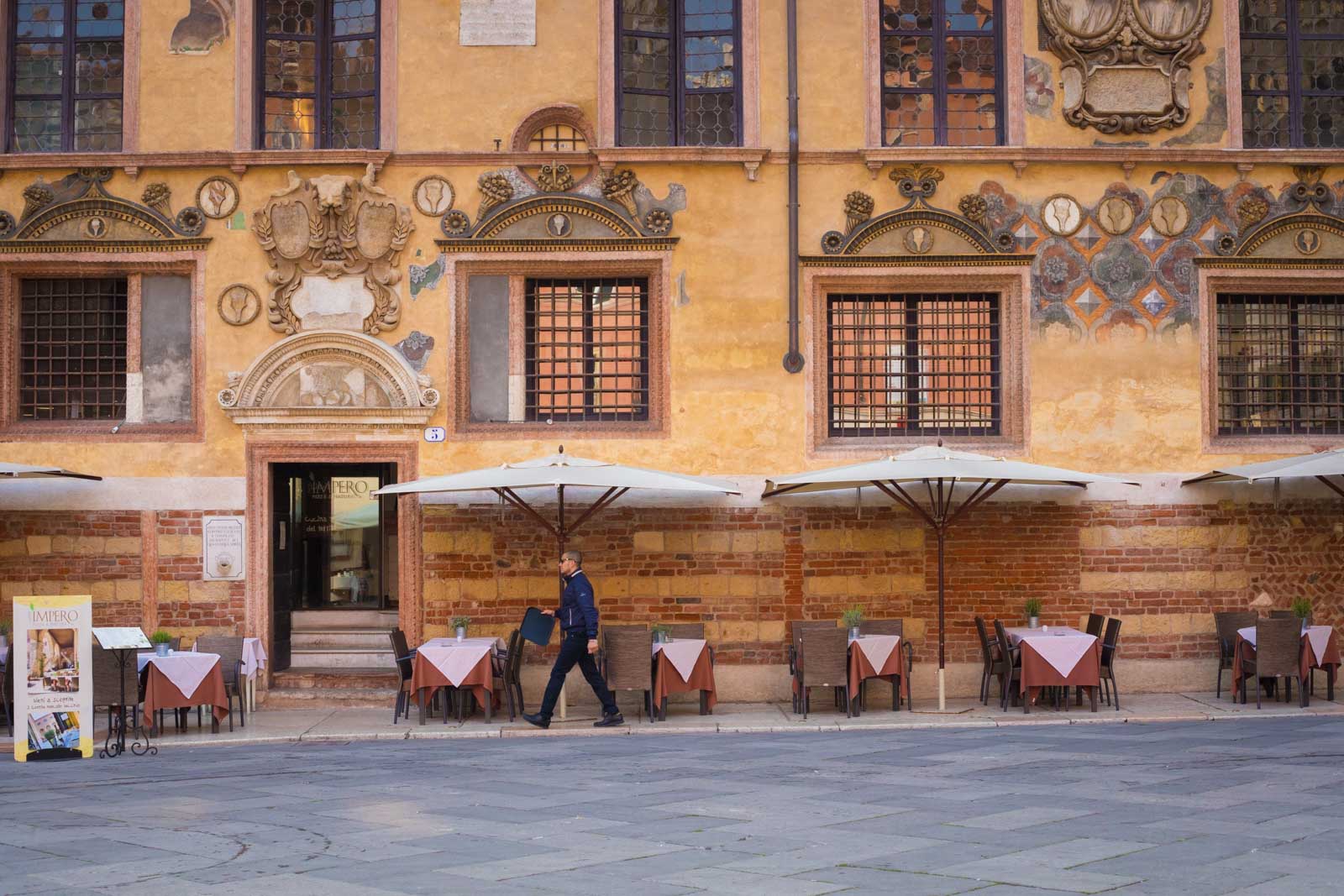 A waiter walks by a caffé in Piazza dei Signori, Verona.