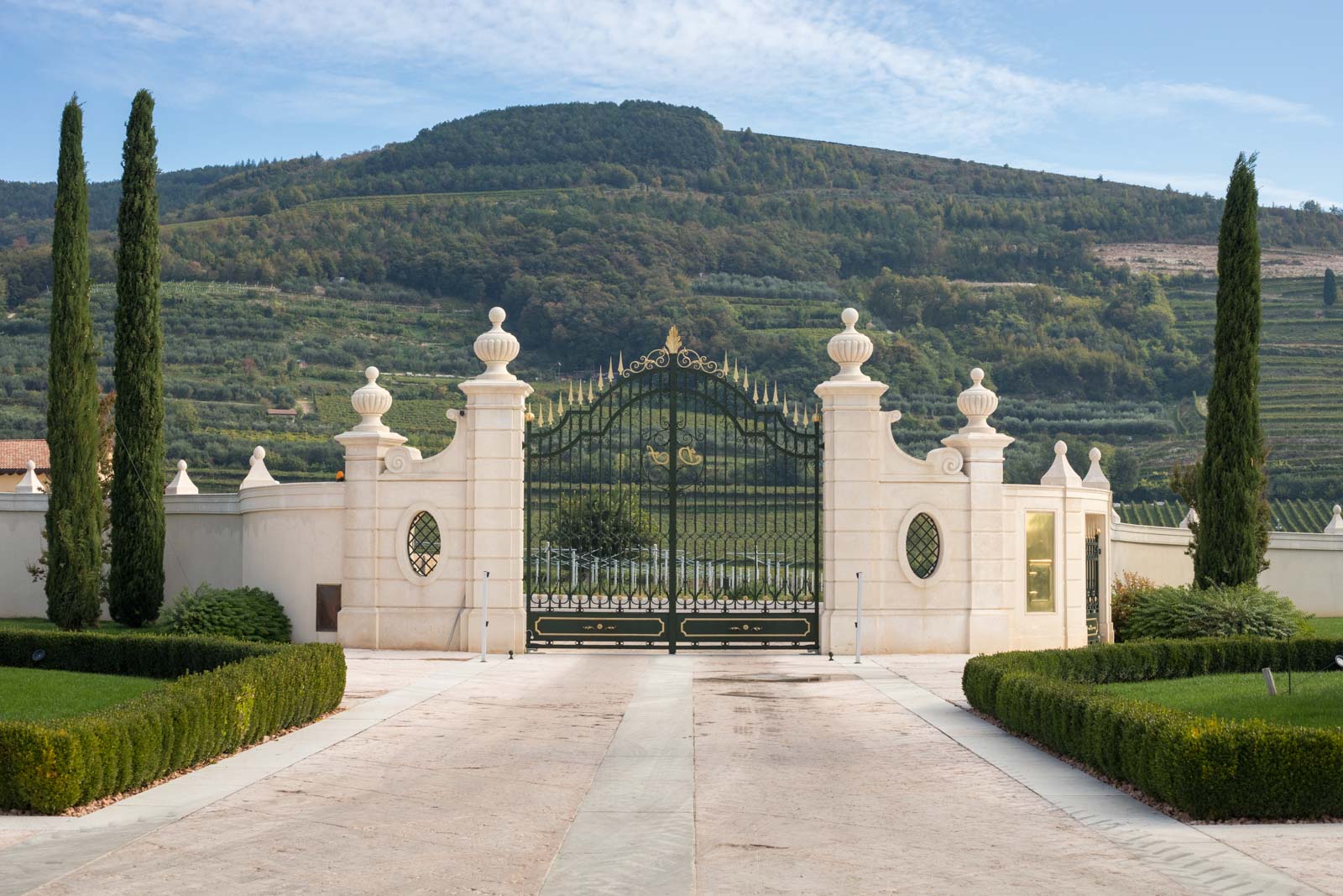 The entrance gate to the winery with vineyards on the hillside in the distance. ©Kevin Day/Opening a Bottle