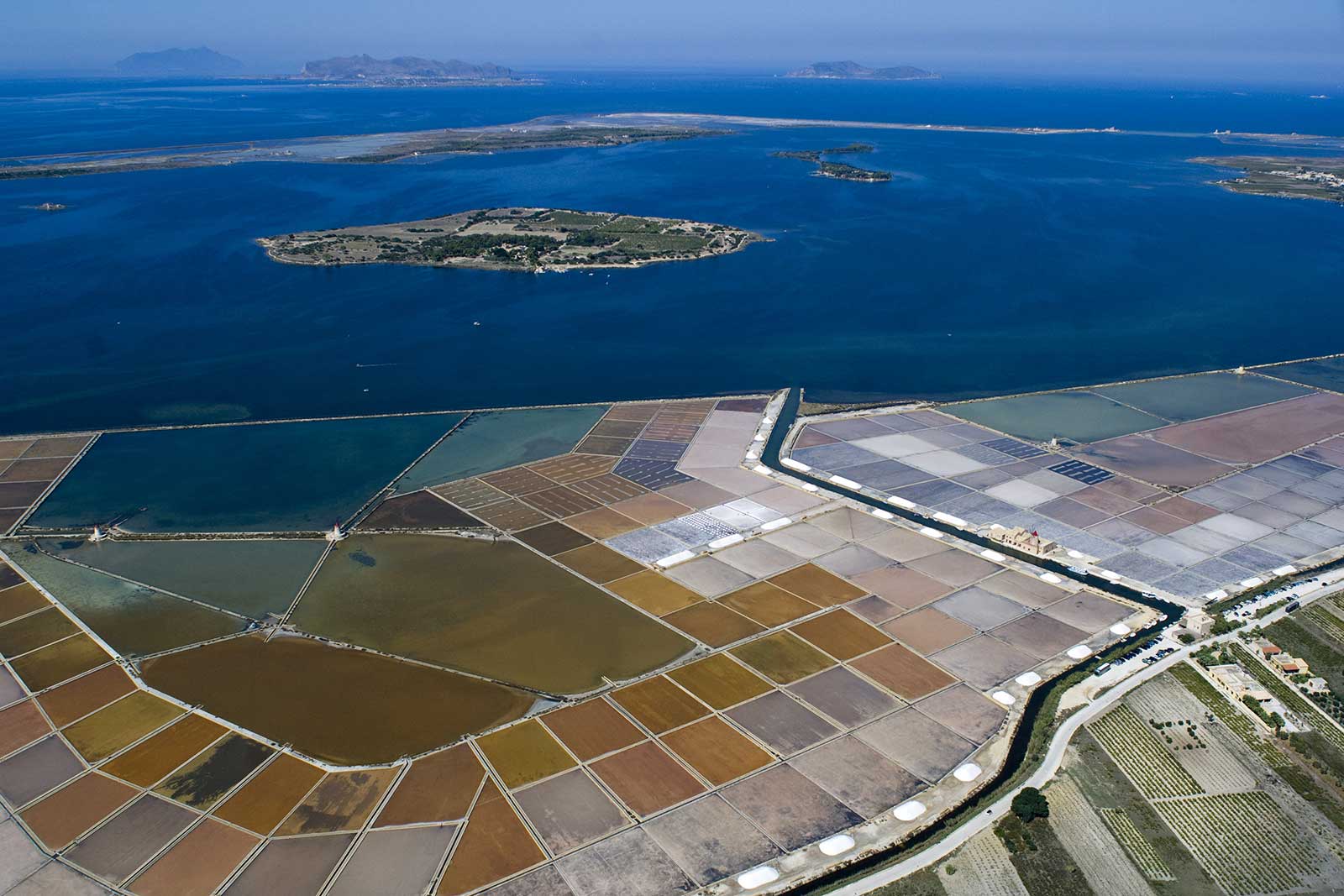 The island of Mozia is seen in the middle of the lagoon, with the famous salt pans running along the shore. Stock photo.