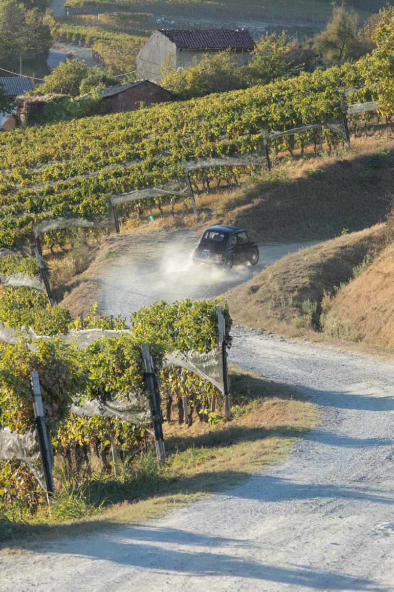 An antique car drives up the roads of Barolo, Italy