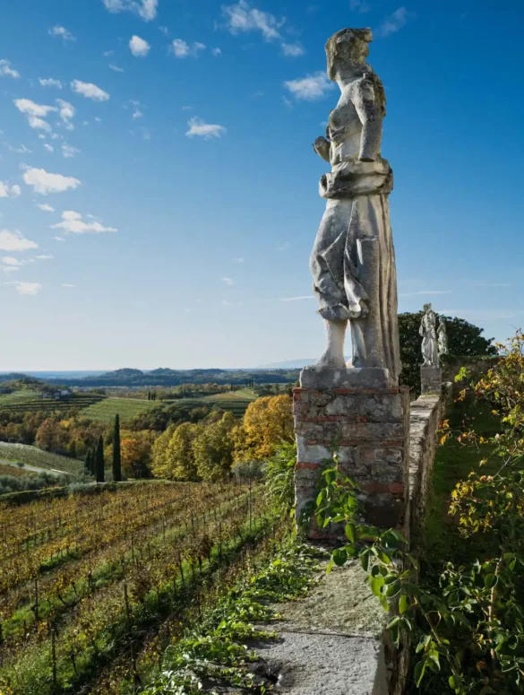 A statue looks over the vineyards of Rosazzo, Italy and a rose garden, Friuli Italy.