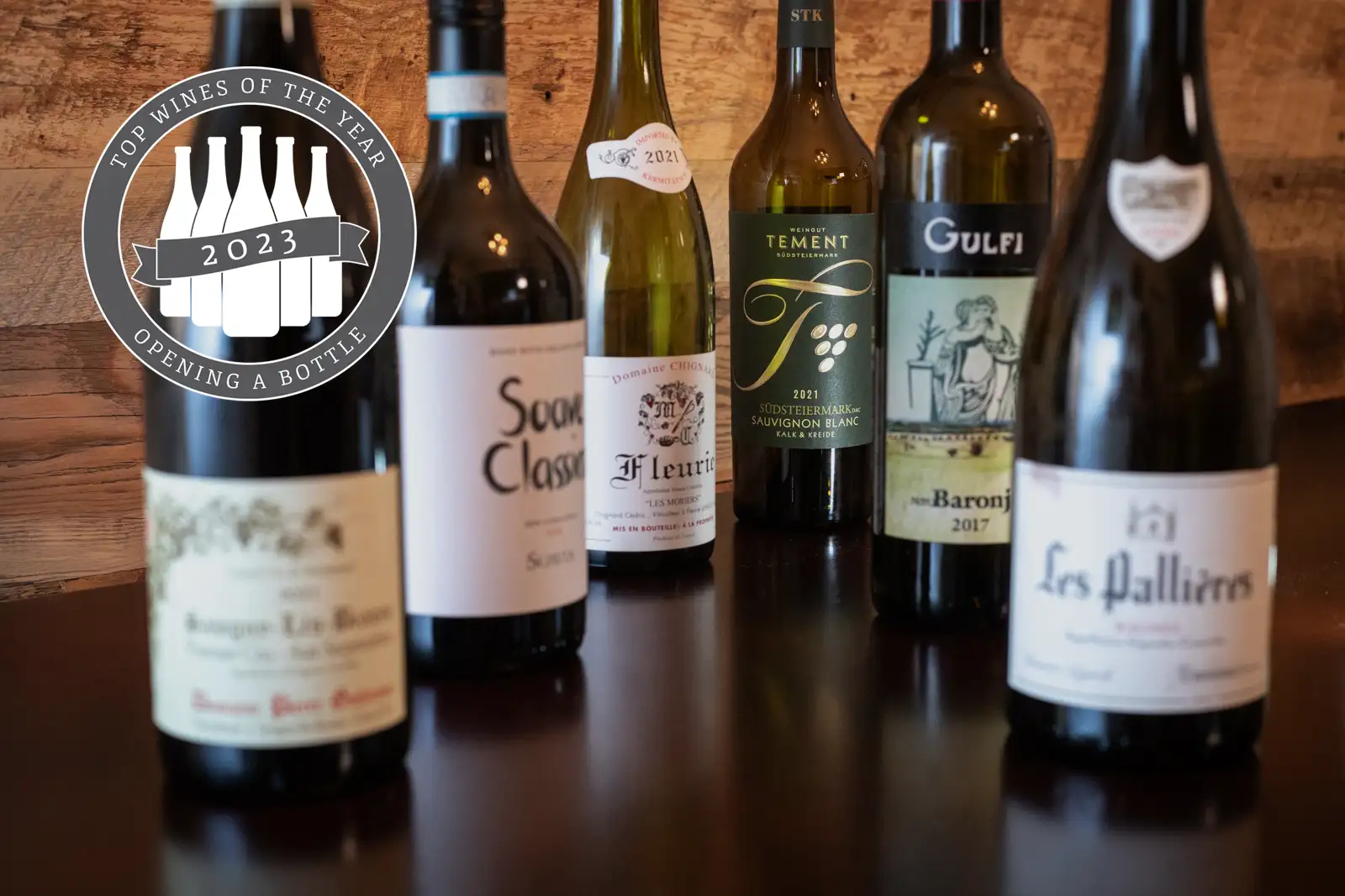 Opening a Bottle's Top 12 Wines of 2023: six wine bottles on a wood table