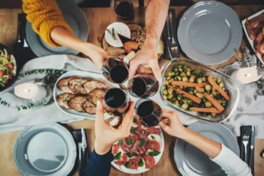 Friends toast with red wine glasses over a dinner inspired by the Mediterranean diet