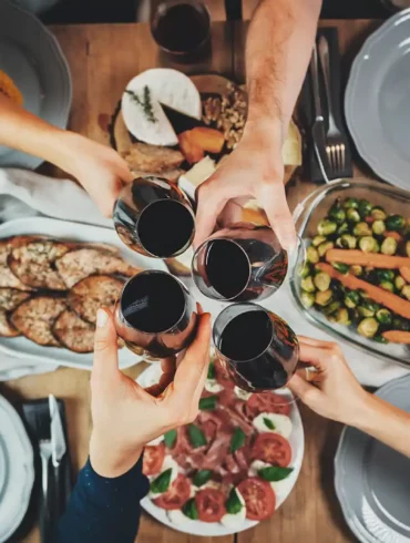 Friends toast with red wine glasses over a dinner inspired by the Mediterranean diet