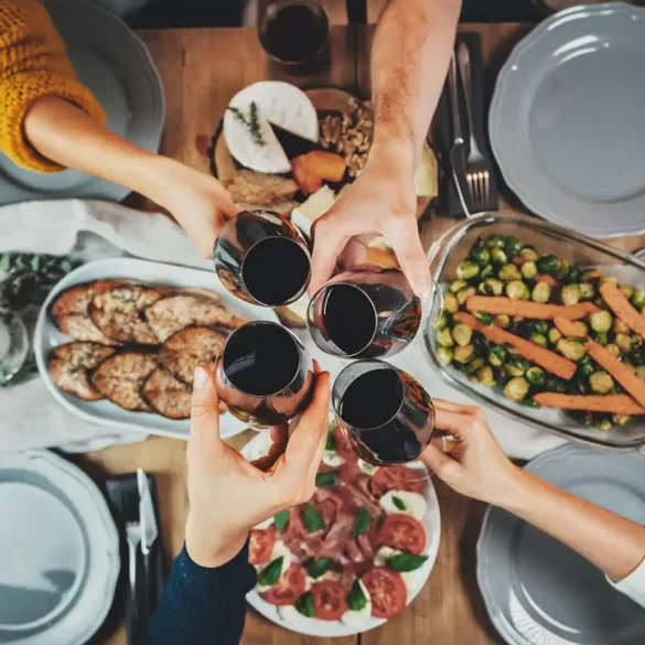 Friends toast with red wine glasses over a dinner inspired by the Mediterranean diet