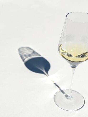 white wine in a wine glass on a white background with shadow