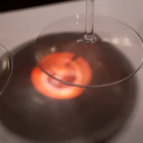 Red light passes through Brunello wine onto stemware base and white table cloth