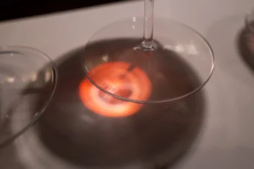 Red light passes through Brunello wine onto stemware base and white table cloth