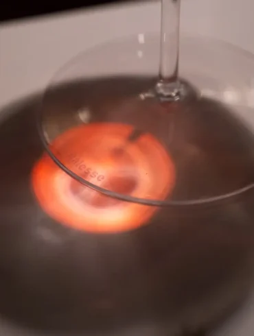 Red light passes through Brunello wine onto stemware base and white table cloth