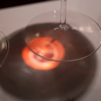 Red light passes through Brunello wine onto stemware base and white table cloth
