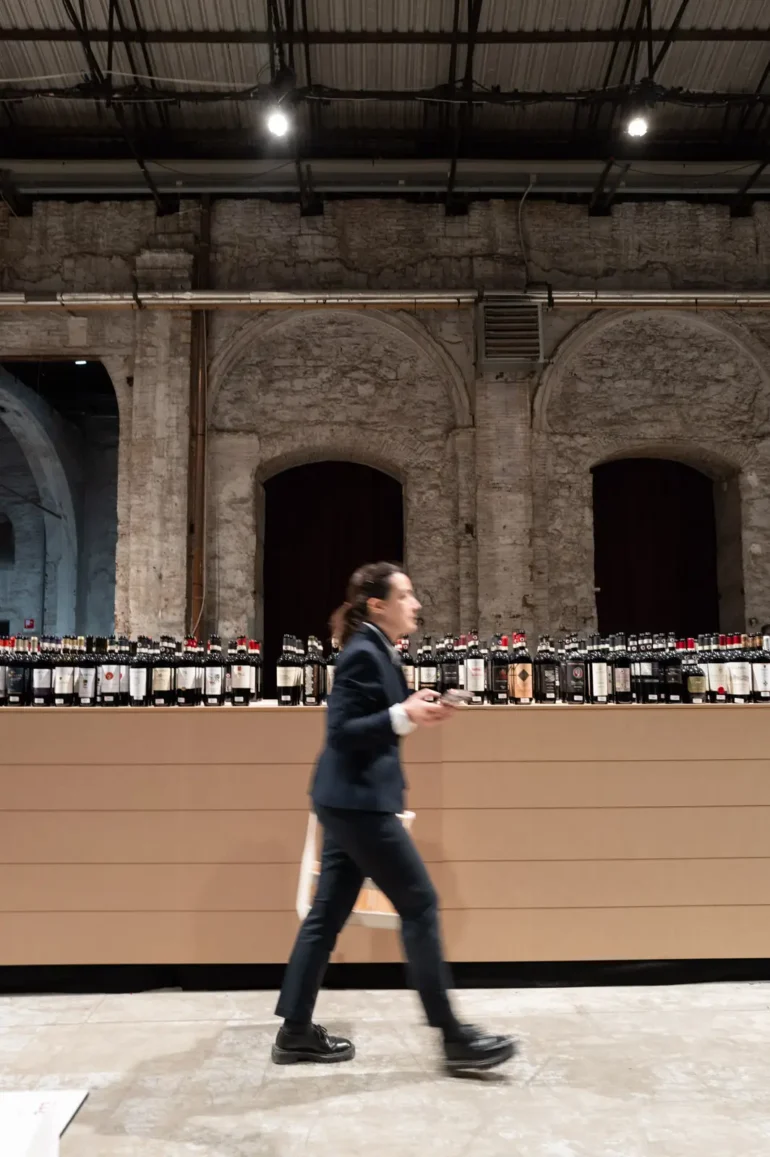 Sommelier walking by wine bottles at the Chianti Classico Collection at Stazione Leopolda in Florence